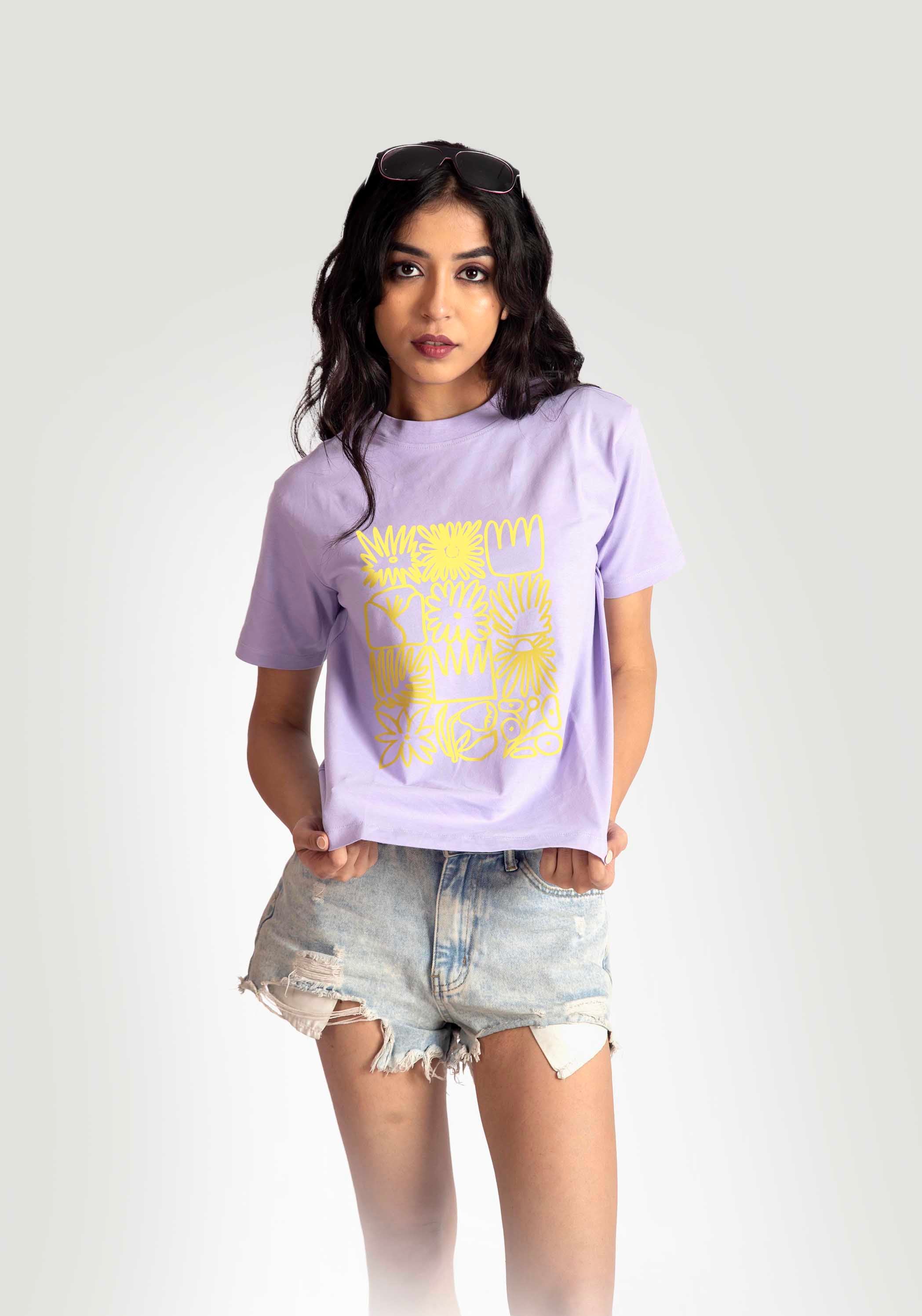 Stylera Woman wearing lavender graphic t-shirt for women with yellow floral design and distressed denim shorts