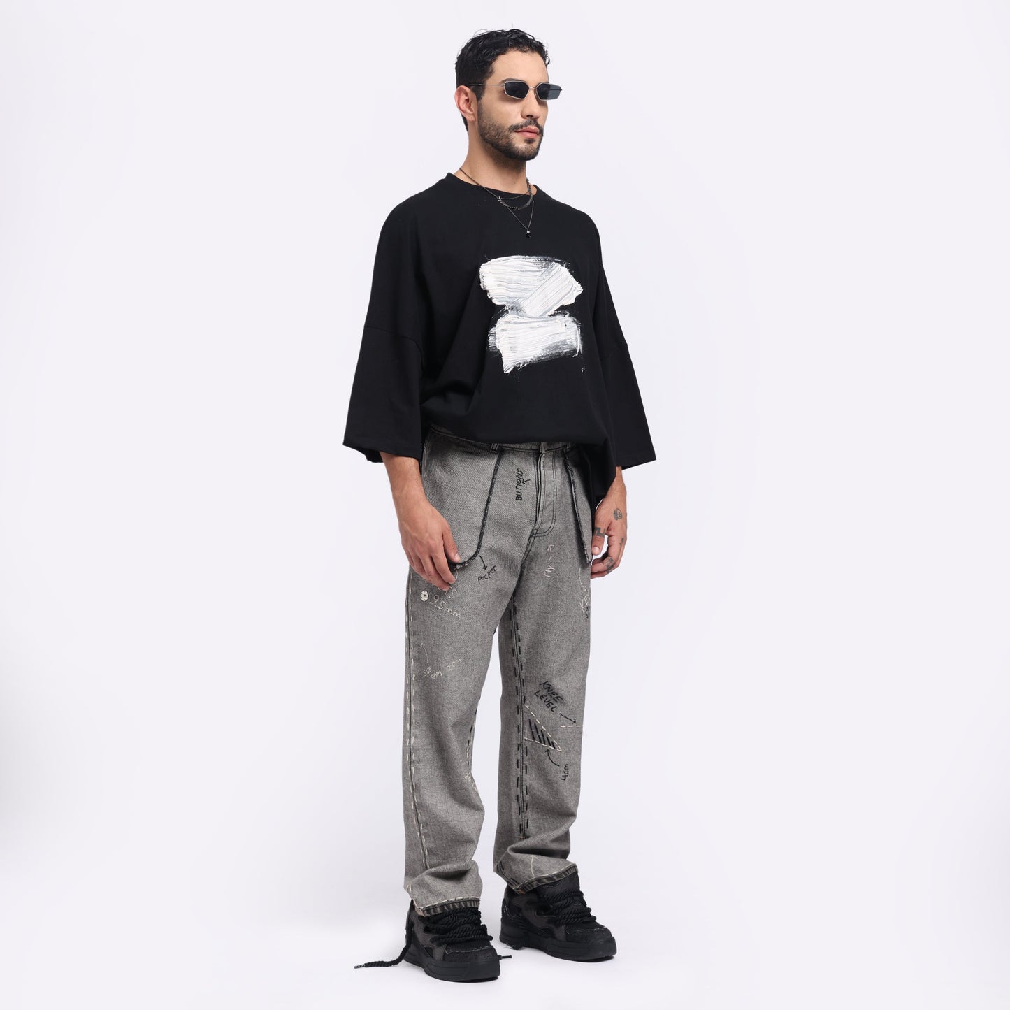 Stylera modern streetwear black t-shirt featuring a unique graphic design, paired with gray baggy pants