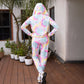 Back view of a woman wearing a multicolor neon jacket and joggers set with a hood and a colorful design