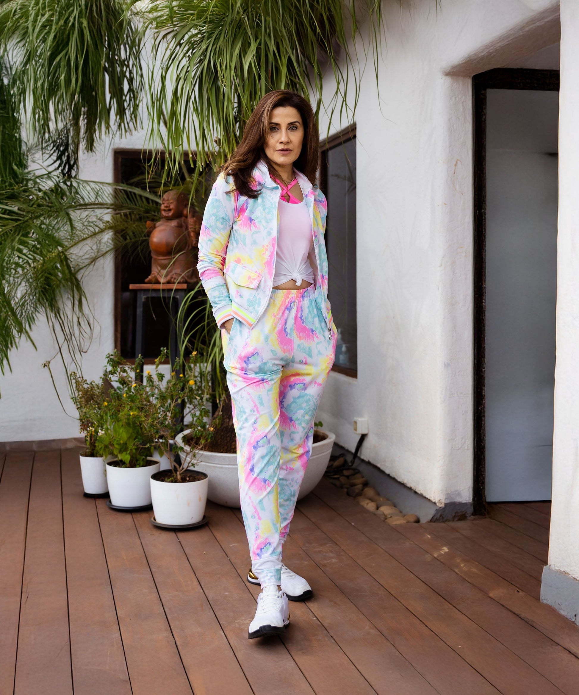Woman wearing a multicolor neon jacket and joggers set with a stylish pink top and sneakers