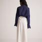 Back view of navy blue oversized cotton shirt by Stylera worn with white midi skirt and heels