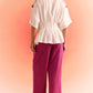 Woman wearing off white embroidered cord set top with wide sleeves paired with magenta wide-leg pants