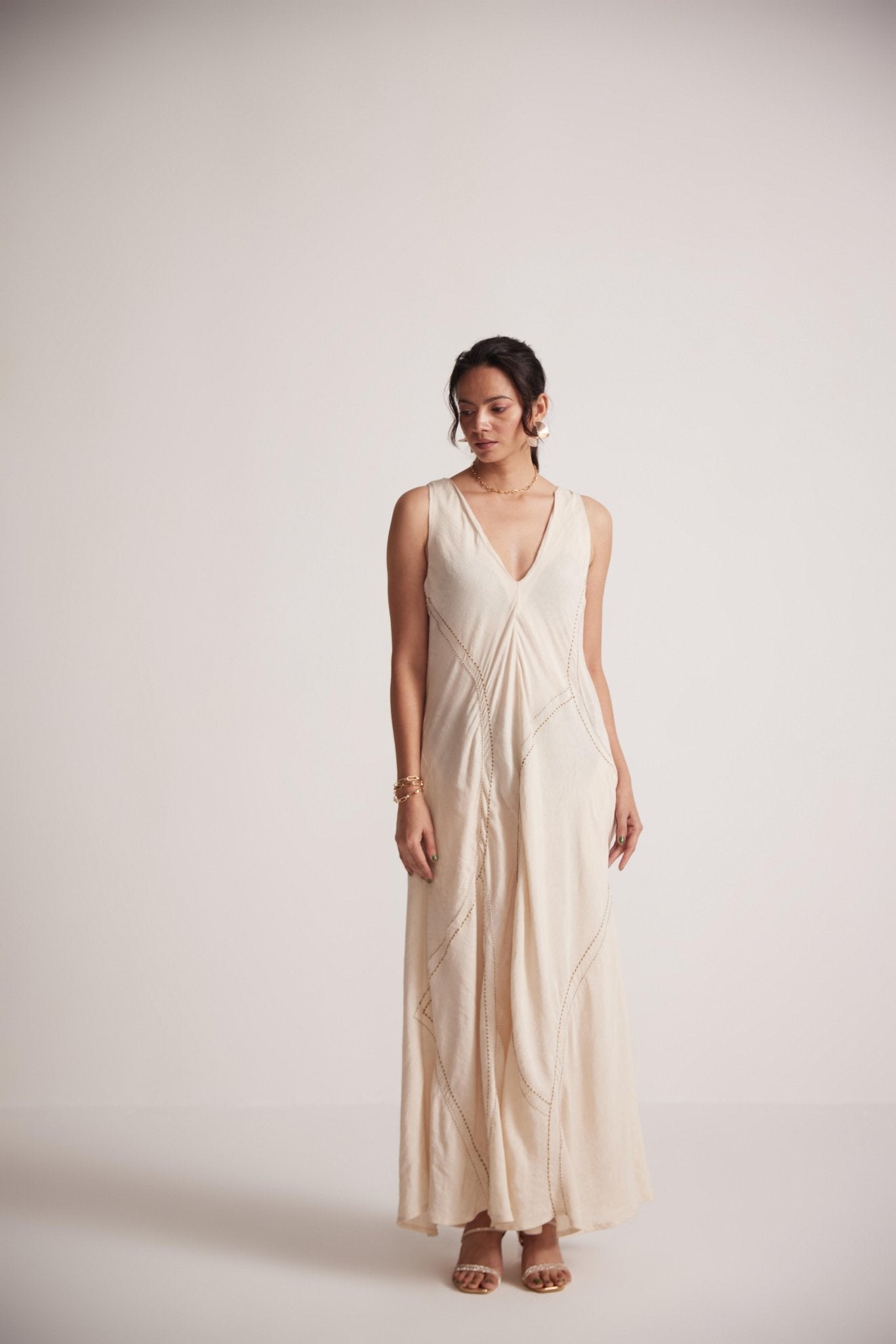 Woman wearing off-white event dress by Stylera with intricate embroidery and sleeveless design