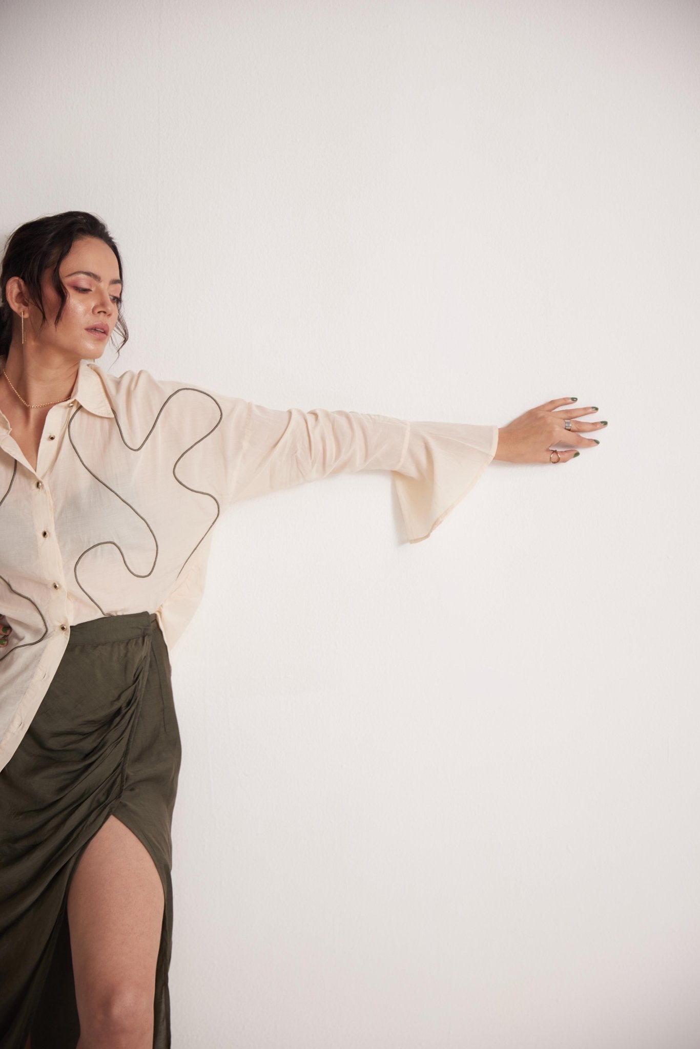 Stylera off-white oversized cotton shirt worn by model styled with a high-slit olive green skirt