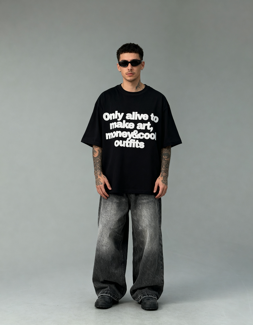 Person wearing a black t-shirt with text and gray pants on a gray background