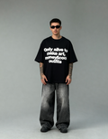 Person wearing a black t-shirt with text and gray pants on a gray background