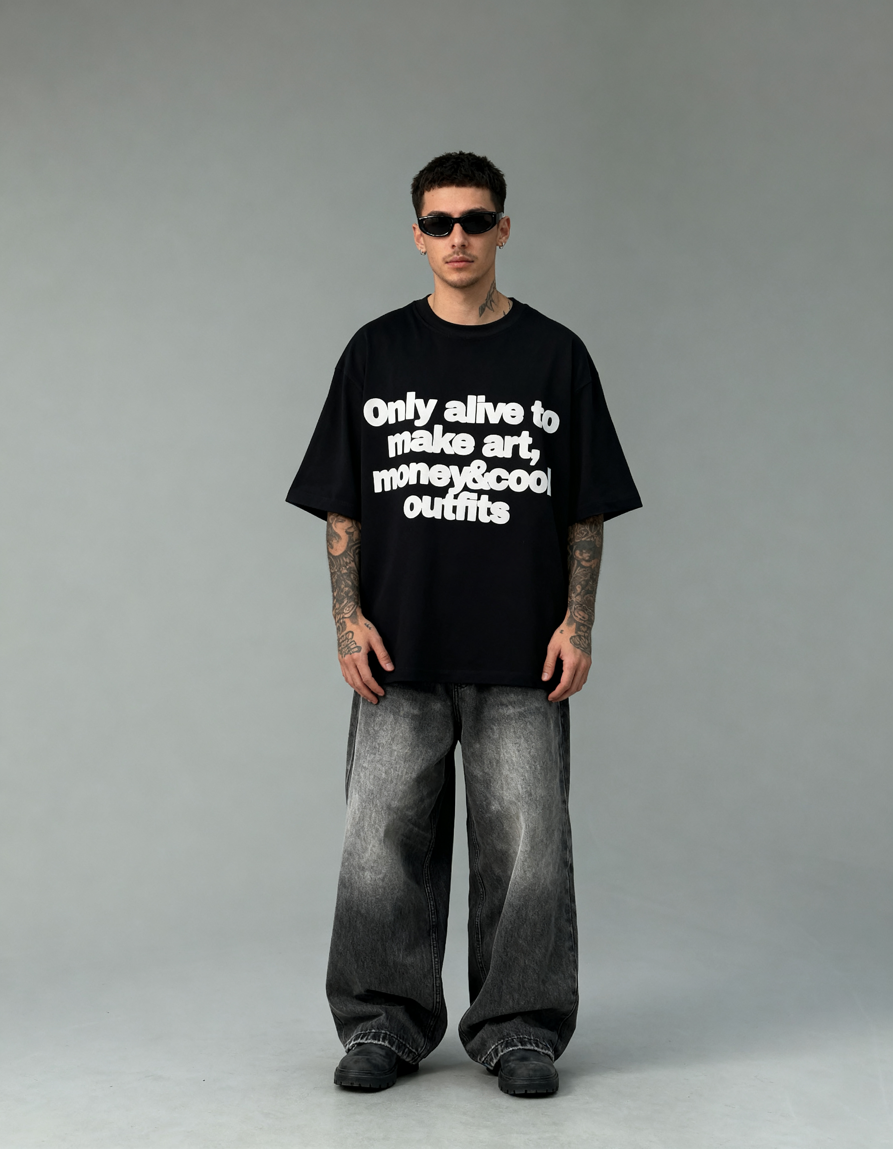 Person wearing a black t-shirt with text and gray pants on a gray background