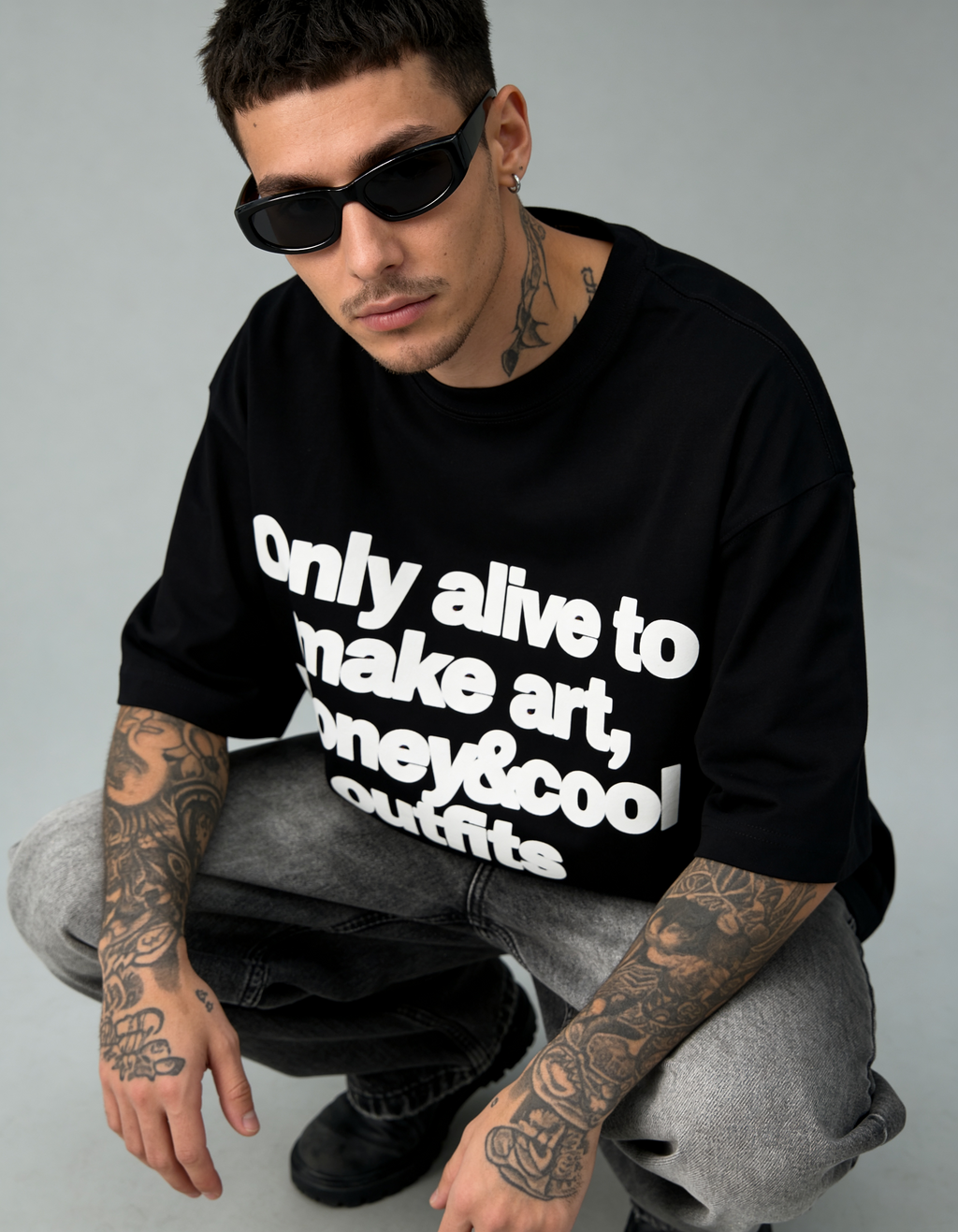 Person wearing a black hoodie with text, sitting on a gray background