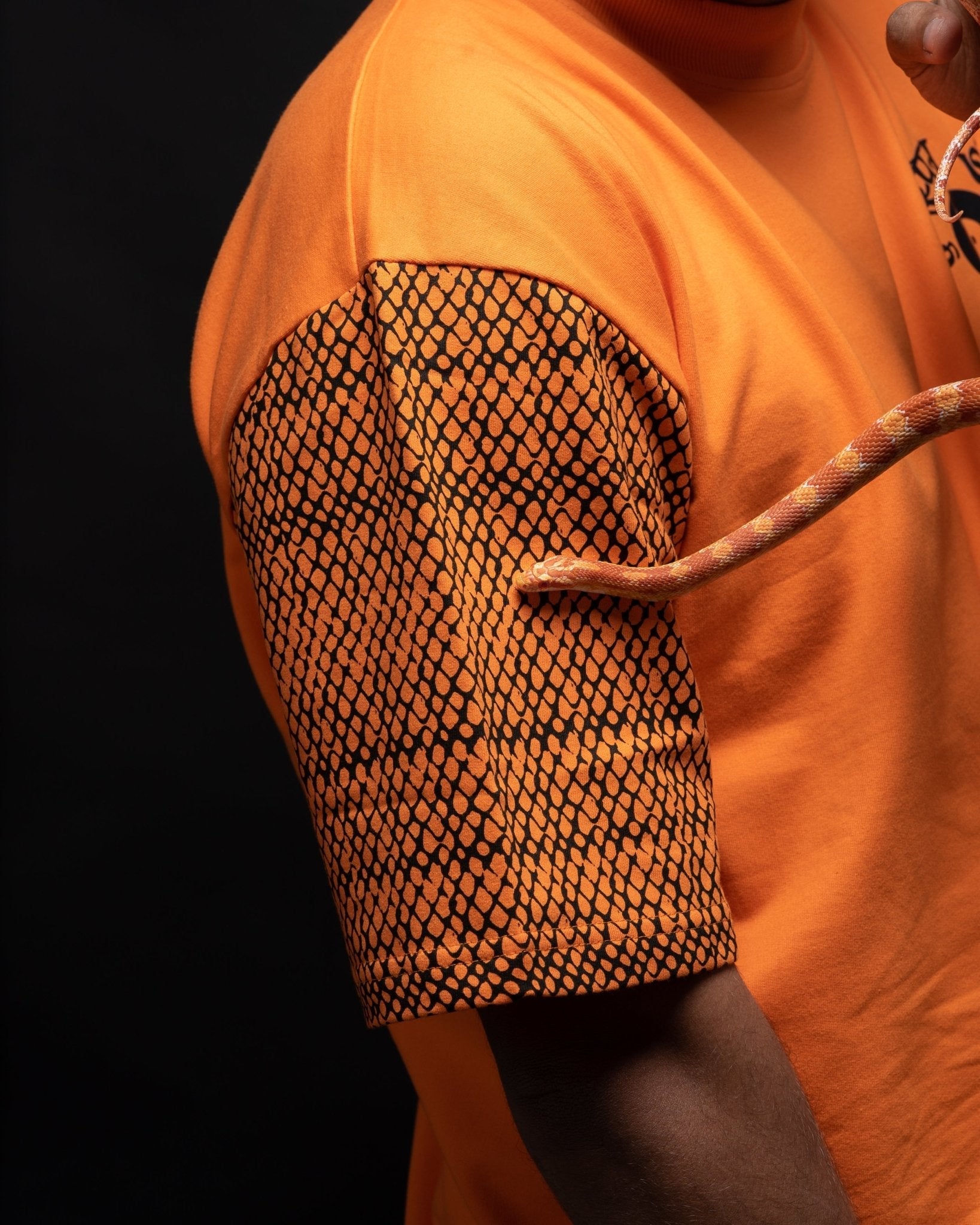 Stylera oversized orange streetwear tee with black scaled pattern sleeve and snake prop
