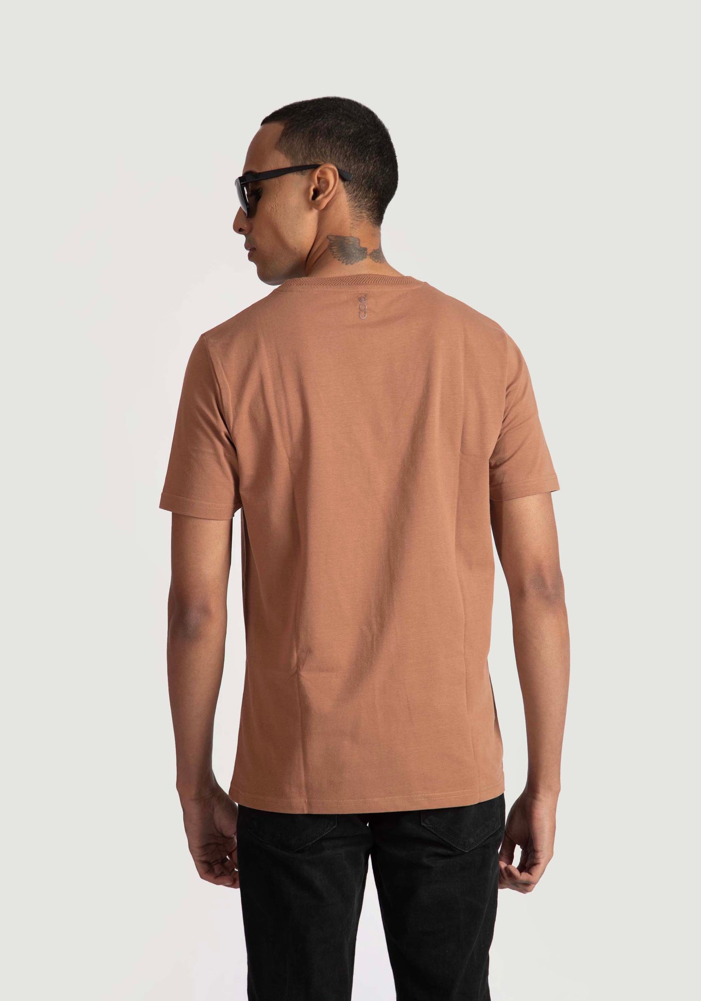 Back view of man wearing brown of Stylera regular fit casual tee paired with black pants