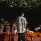 Men's oversize floral button down shirt displayed against a vibrant flower backdrop