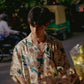 Man wearing an oversize floral button down shirt while arranging flowers outdoors