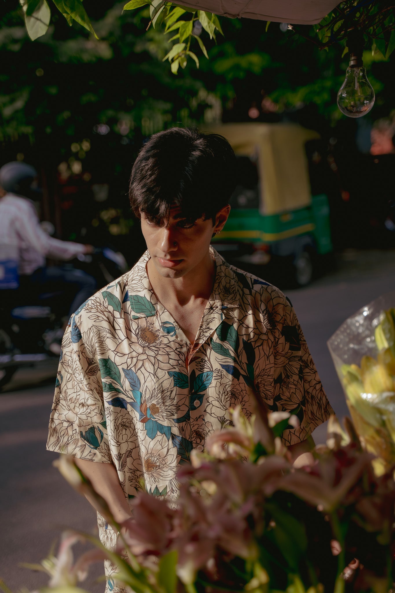 Man wearing an oversize floral button down shirt while arranging flowers outdoors