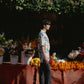 Model wearing an oversize floral button down shirt in a vibrant flower market setting