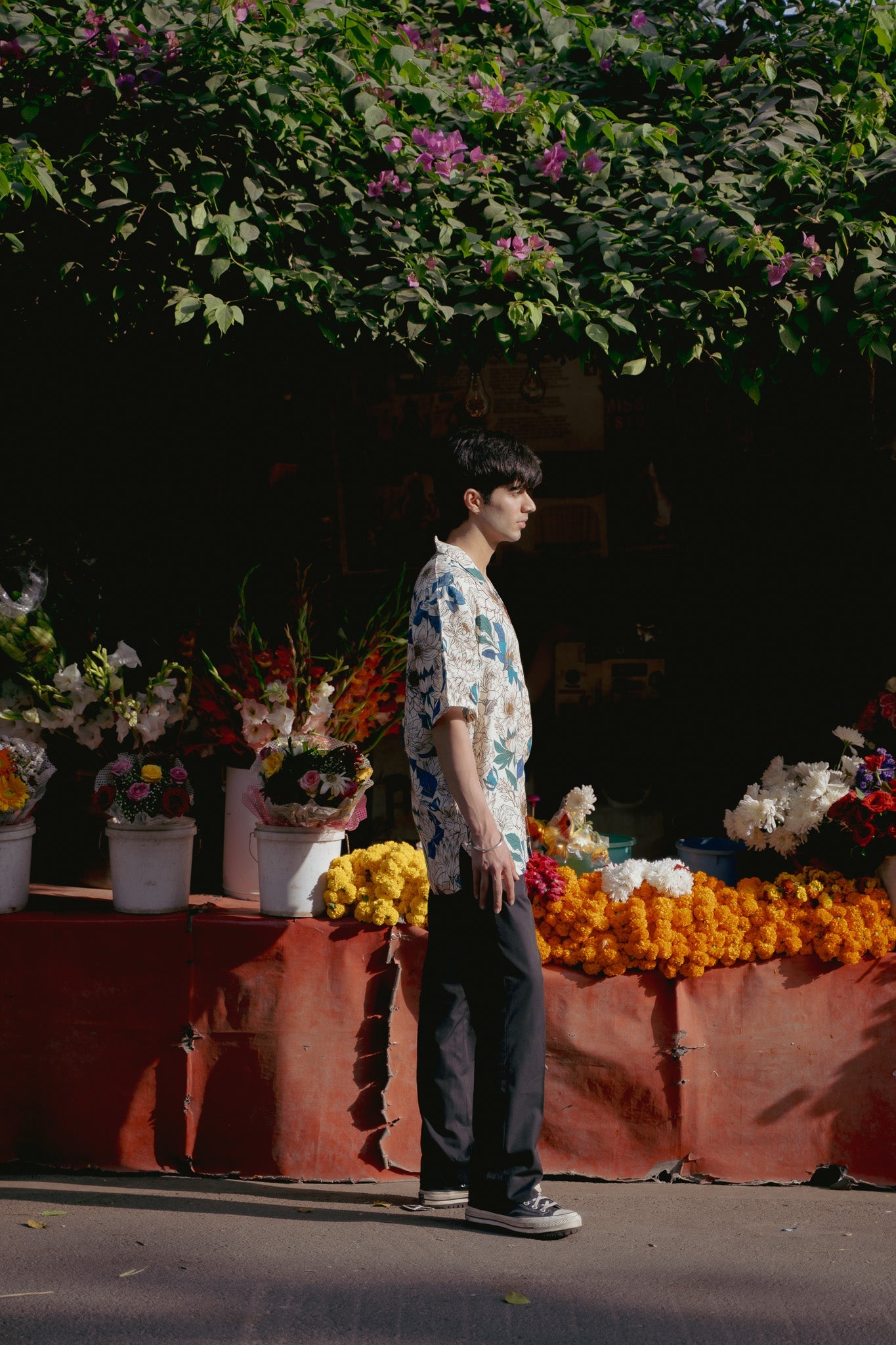 Model wearing an oversize floral button down shirt in a vibrant flower market setting