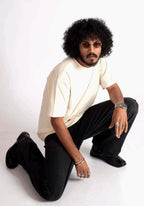 Man wearing oversized almond milk t-shirt paired with black pants and accessories