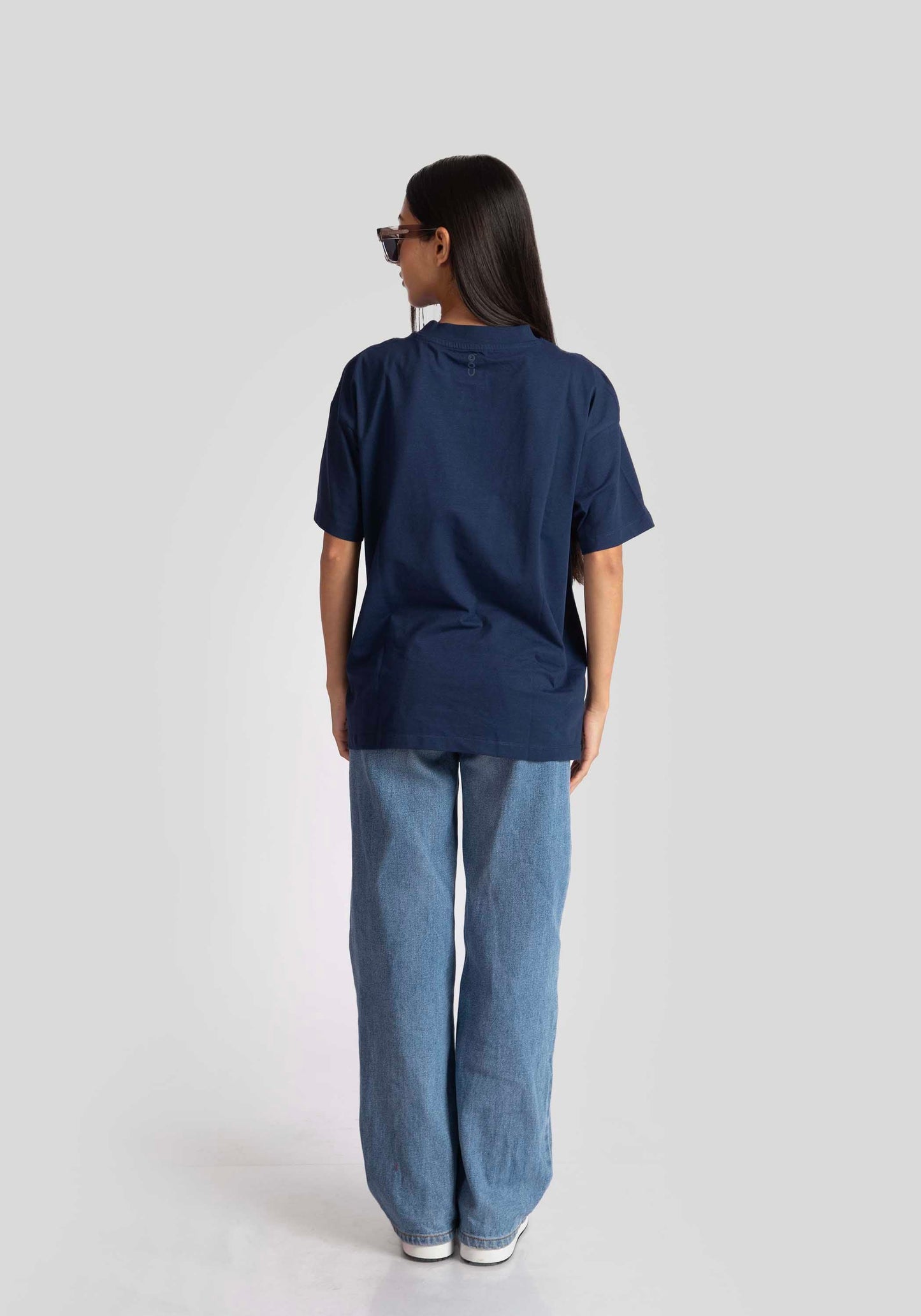 Back view of a woman wearing oversized blue graphic tee for womens paired with light blue wide-leg jeans