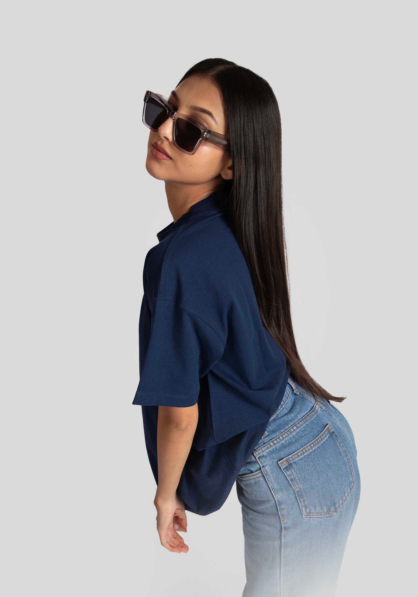 Model wearing oversized blue graphic tee for womens paired with light blue jeans and sunglasses
