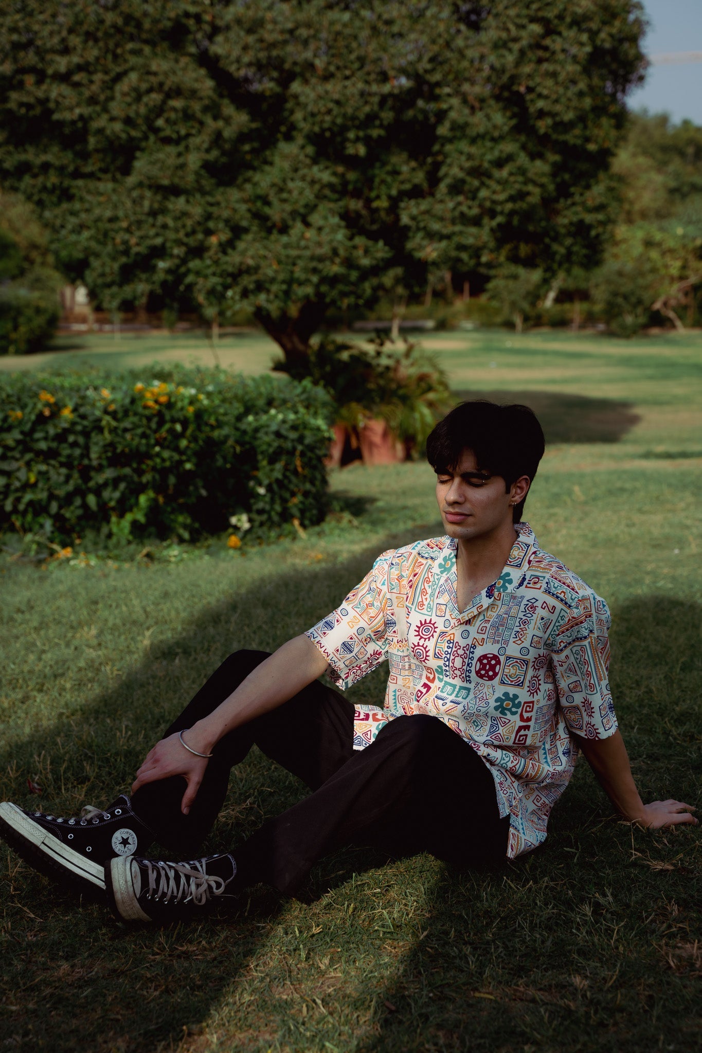 Man sitting outdoors in an oversized casual summer shirt with funky patterns and relaxed fit