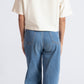 Back view of woman wearing oversized crop top for women in cream color paired with blue jeans