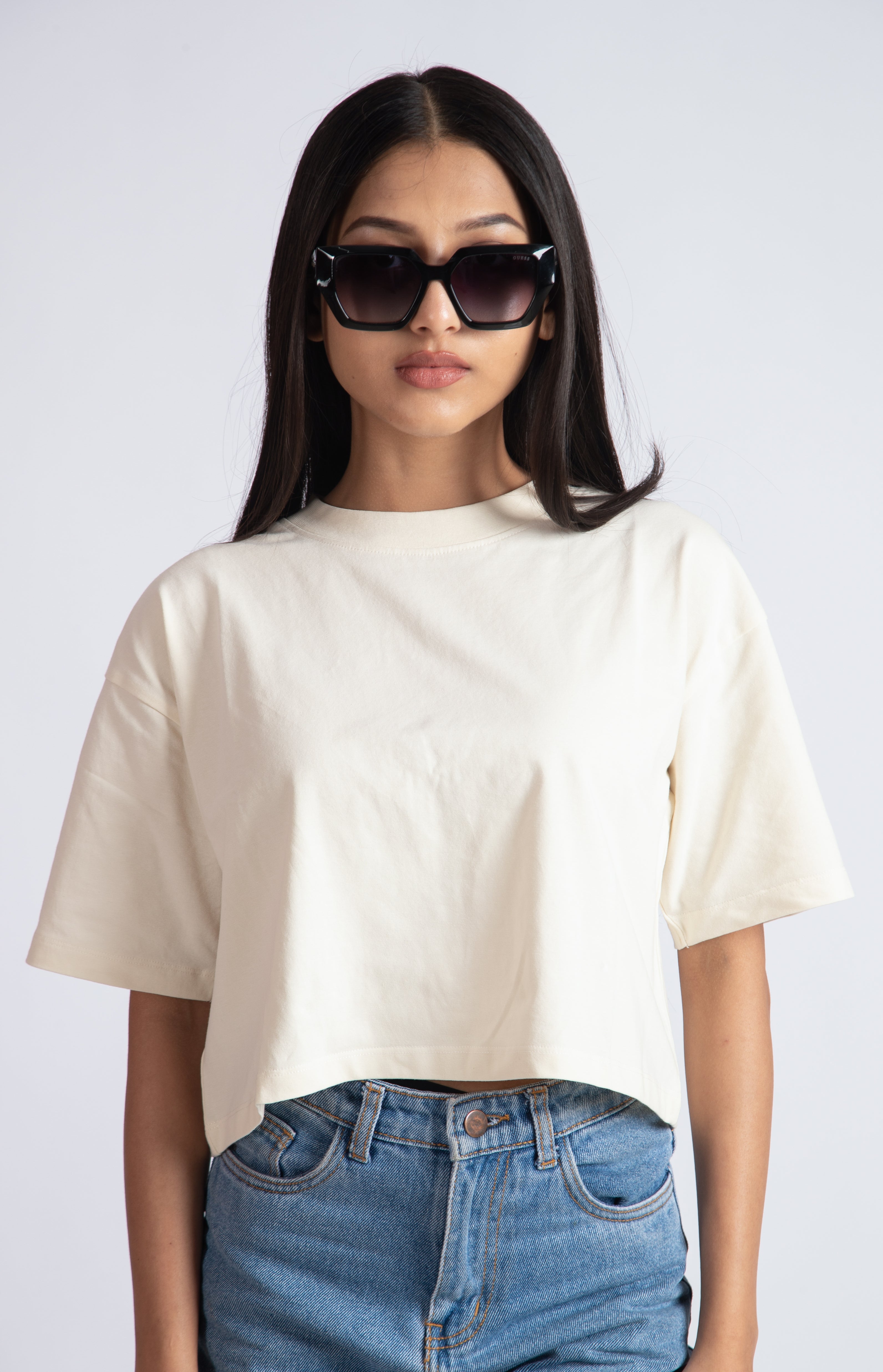 Stylera oversized crop top for women in cream color paired with blue jeans and black sunglasses