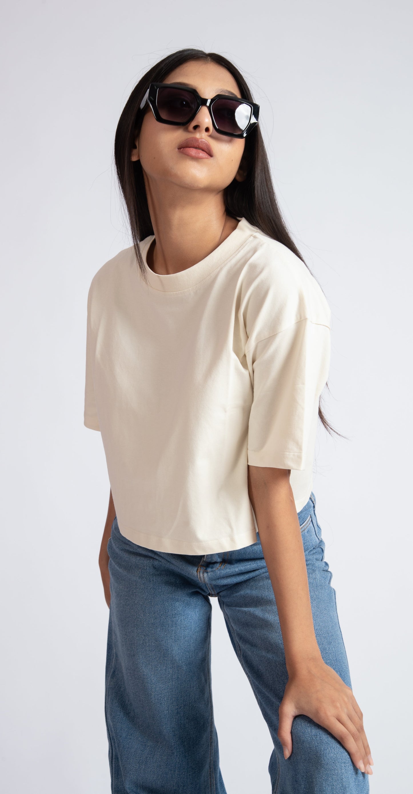 Stylera oversized crop top for women in beige paired with blue jeans and sunglasses