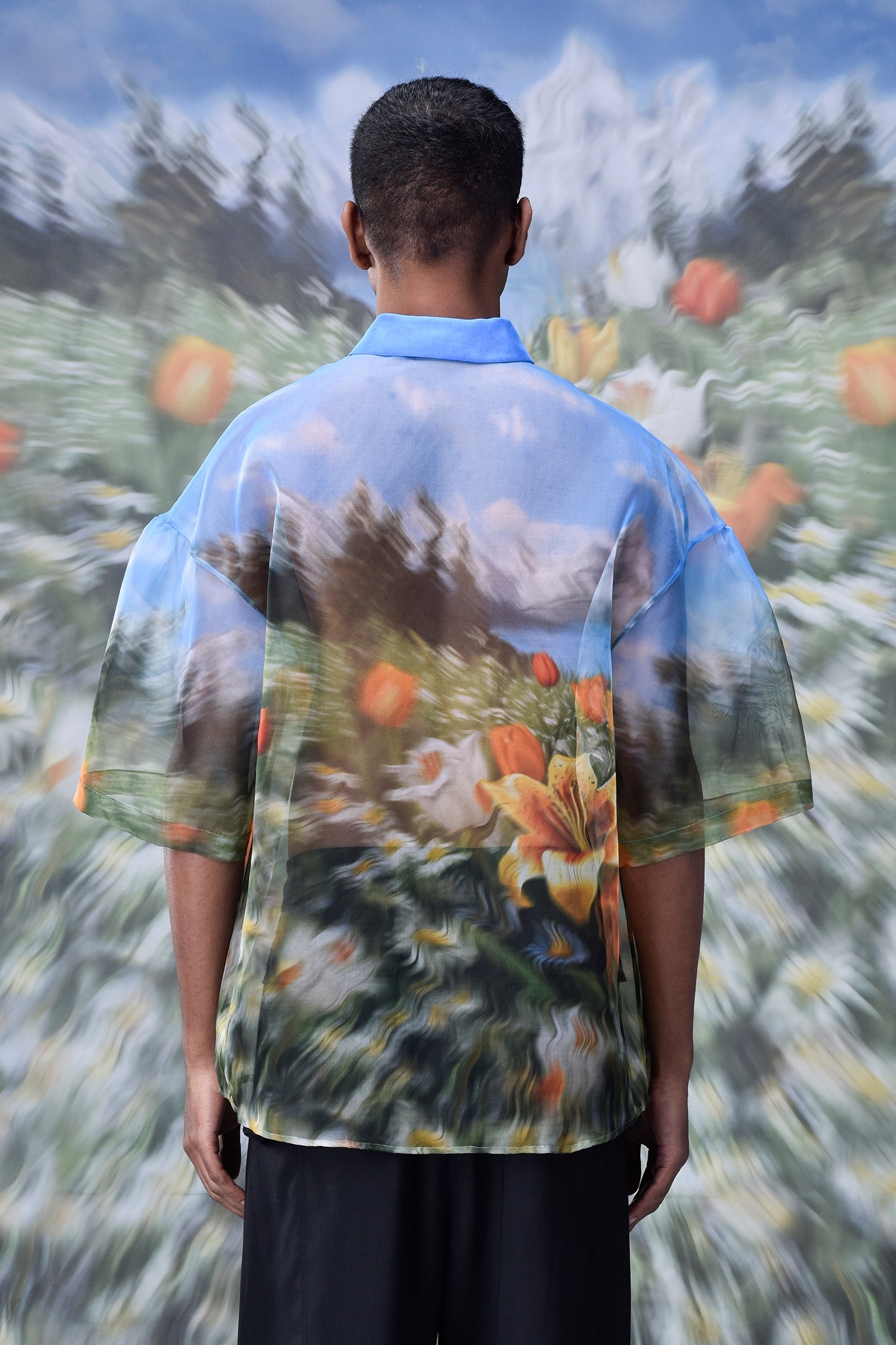 Back view of oversized floral button up shirt by Stylera with colorful flower field design