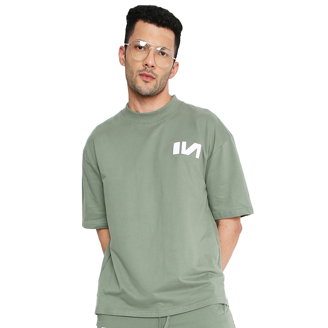 Stylera model wearing an oversized green t-shirt with white chest logo and relaxed fit