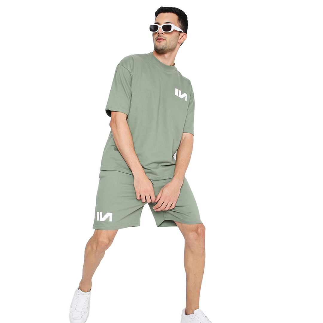 Stylera oversized green t-shirt on male model with matching shorts white logo sunglasses and sneakers