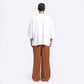 Back view of oversized white tee men paired with brown wide-leg pants for a casual look