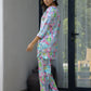 Woman modeling a pastel floral satin pajama set with colorful butterfly design and relaxed fit