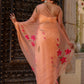 Elegant peach chiffon saree with floral design showcasing vibrant pink flowers and flowing drape
