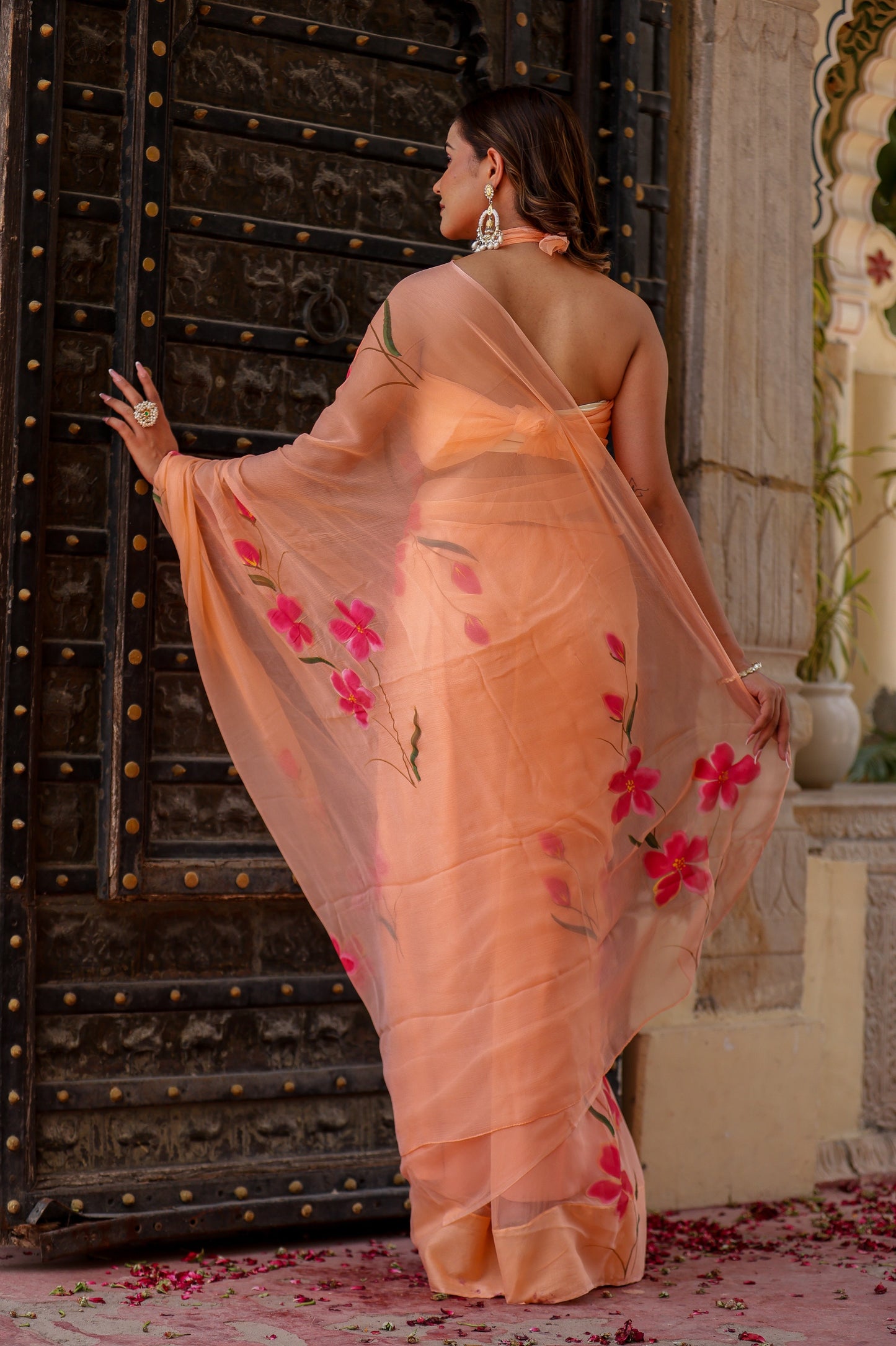 Elegant peach chiffon saree with floral design showcasing vibrant pink flowers and flowing drape