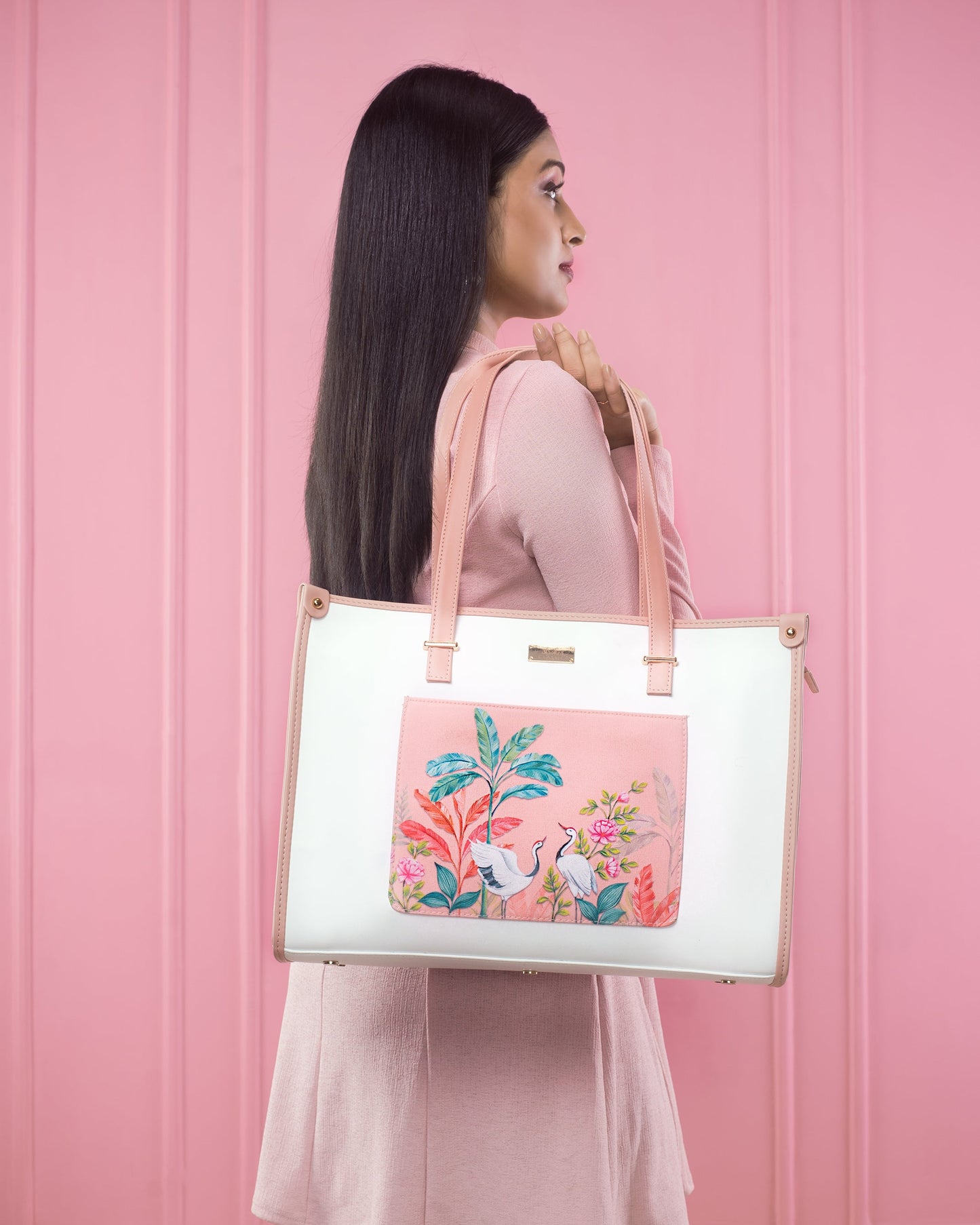 Peach crane paradise tote bag with floral design carried by a woman against a pink background