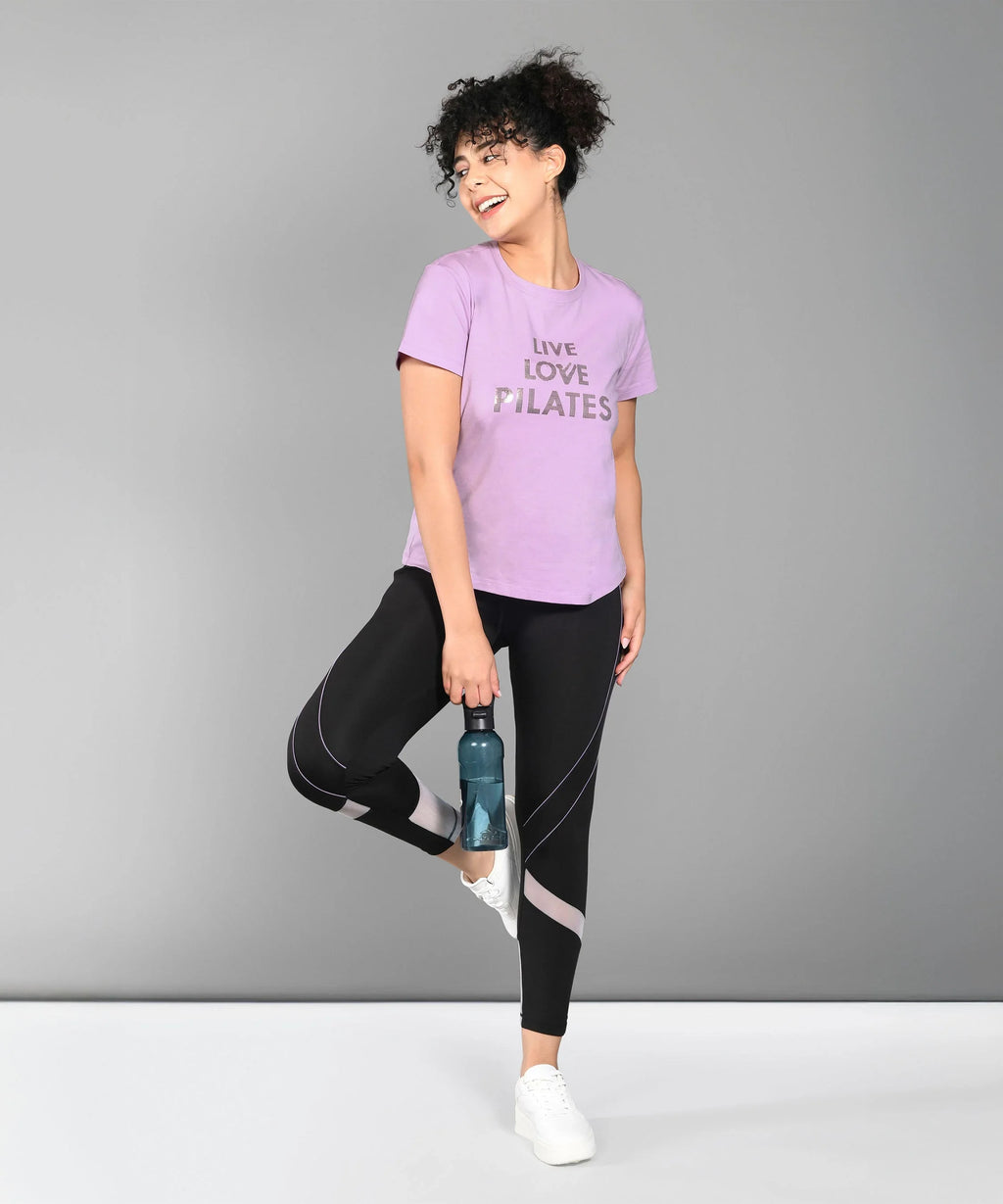 Women wearing a pink t-shirt with 'Live Love Pilates' text, paired with black leggings for Pilates activities