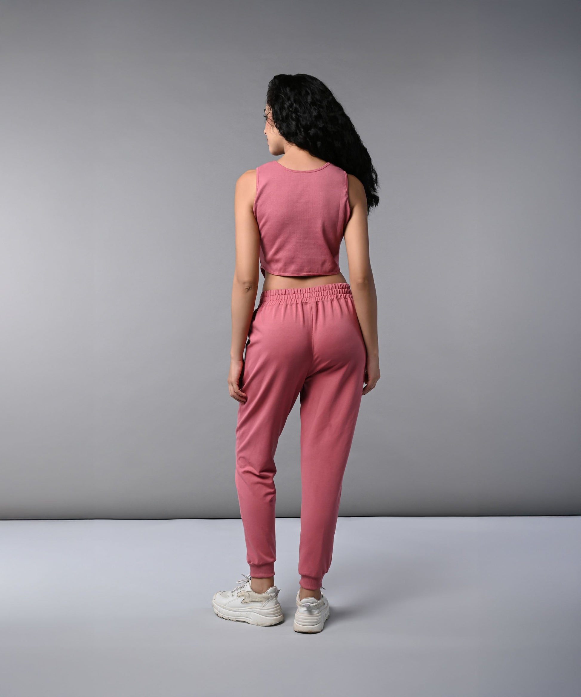 Back view of a model wearing a pink corset crop top with joggers, showcasing a stylish and comfortable outfit