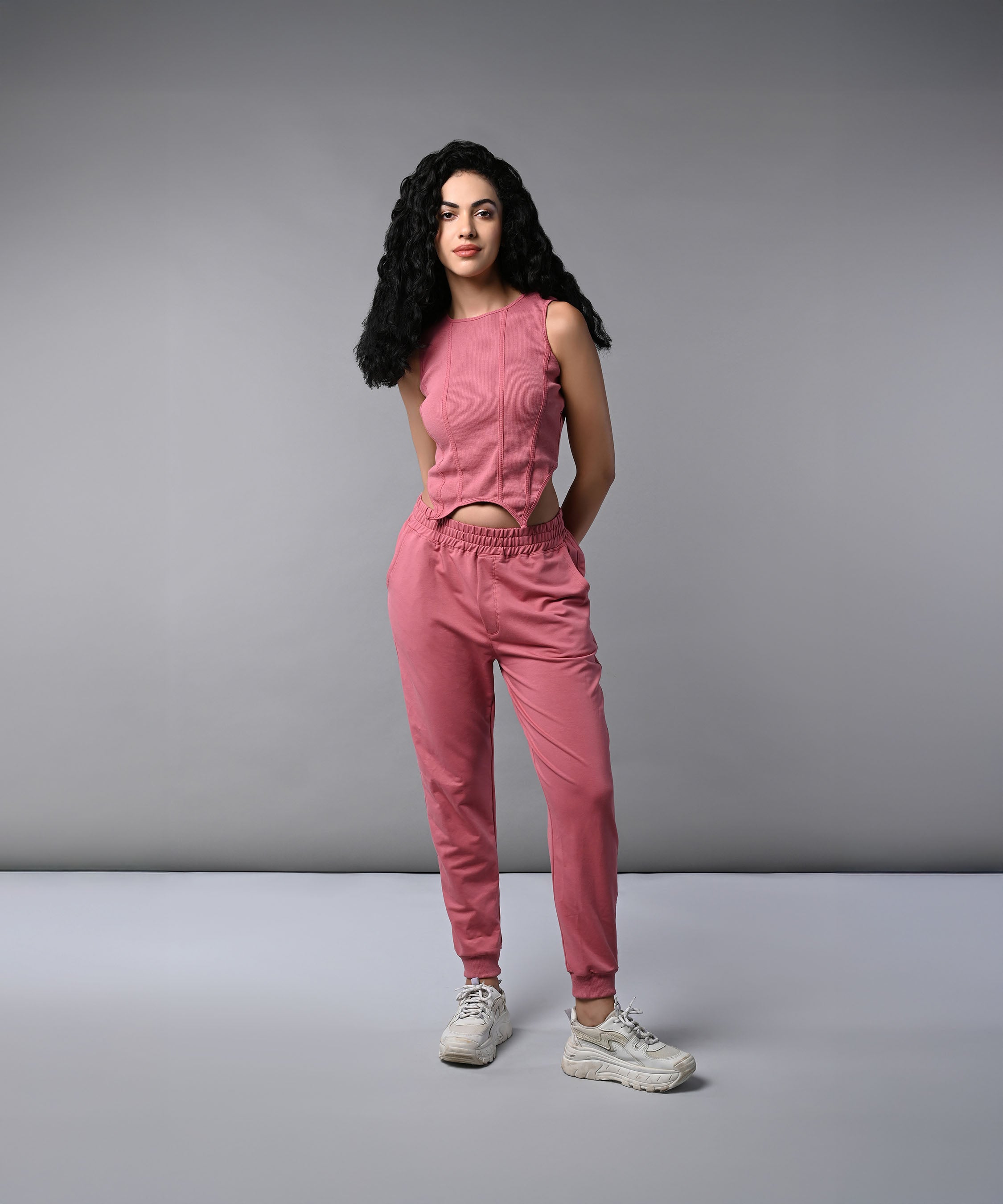 Model wearing a pink corset crop top with joggers, showcasing a stylish and comfortable outfit