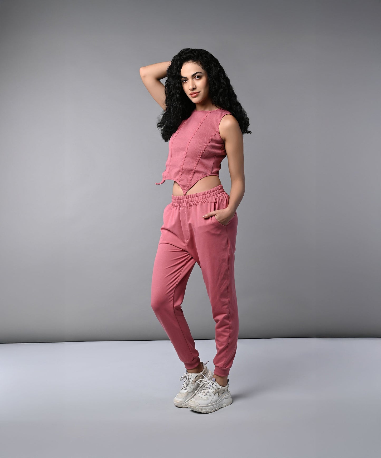 Model wearing a pink corset crop top with joggers, styled for a trendy casual look