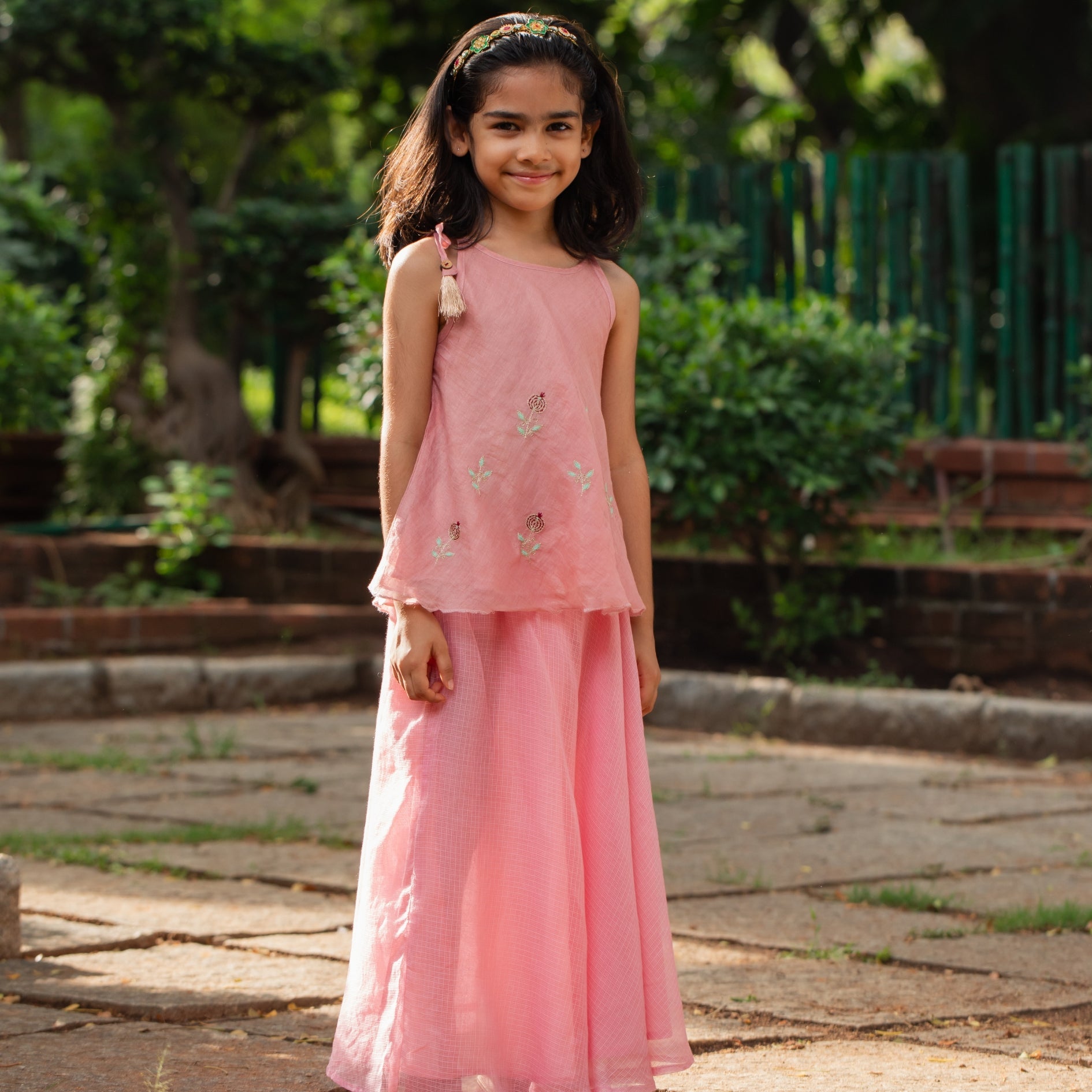 Cute girl wearing a pink festive skirt set with floral embroidery perfect for celebrations