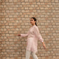 Woman wearing a pink linen top outfit shirt by Stylera paired with white pants walking outdoors