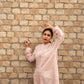Woman wearing a pink linen top outfit by Stylera standing against a brick wall background
