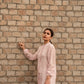 Woman wearing a pink linen top outfit by Stylera standing against a brick wall