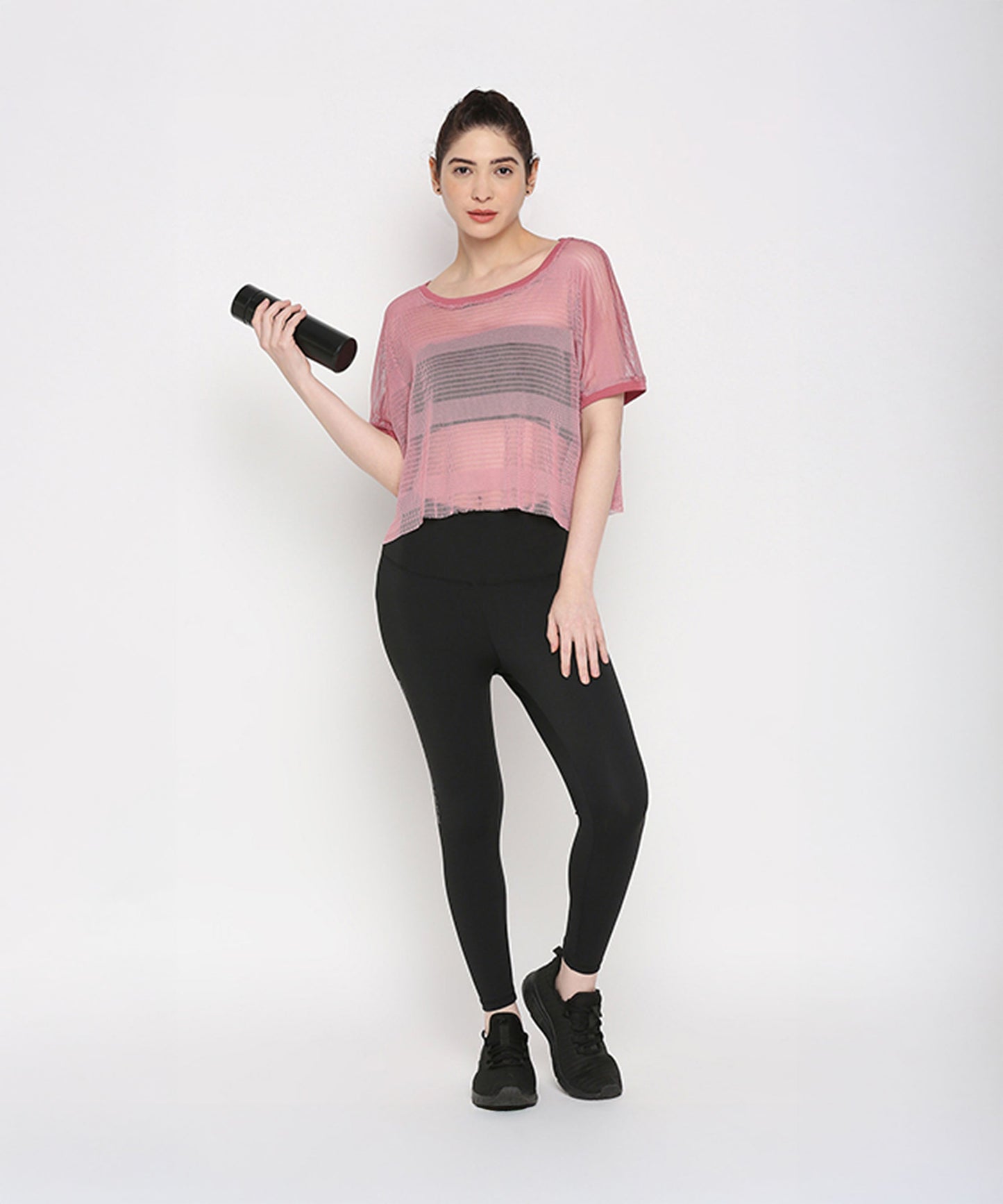 Pink netted top for women paired with black leggings and holding a fitness bottle