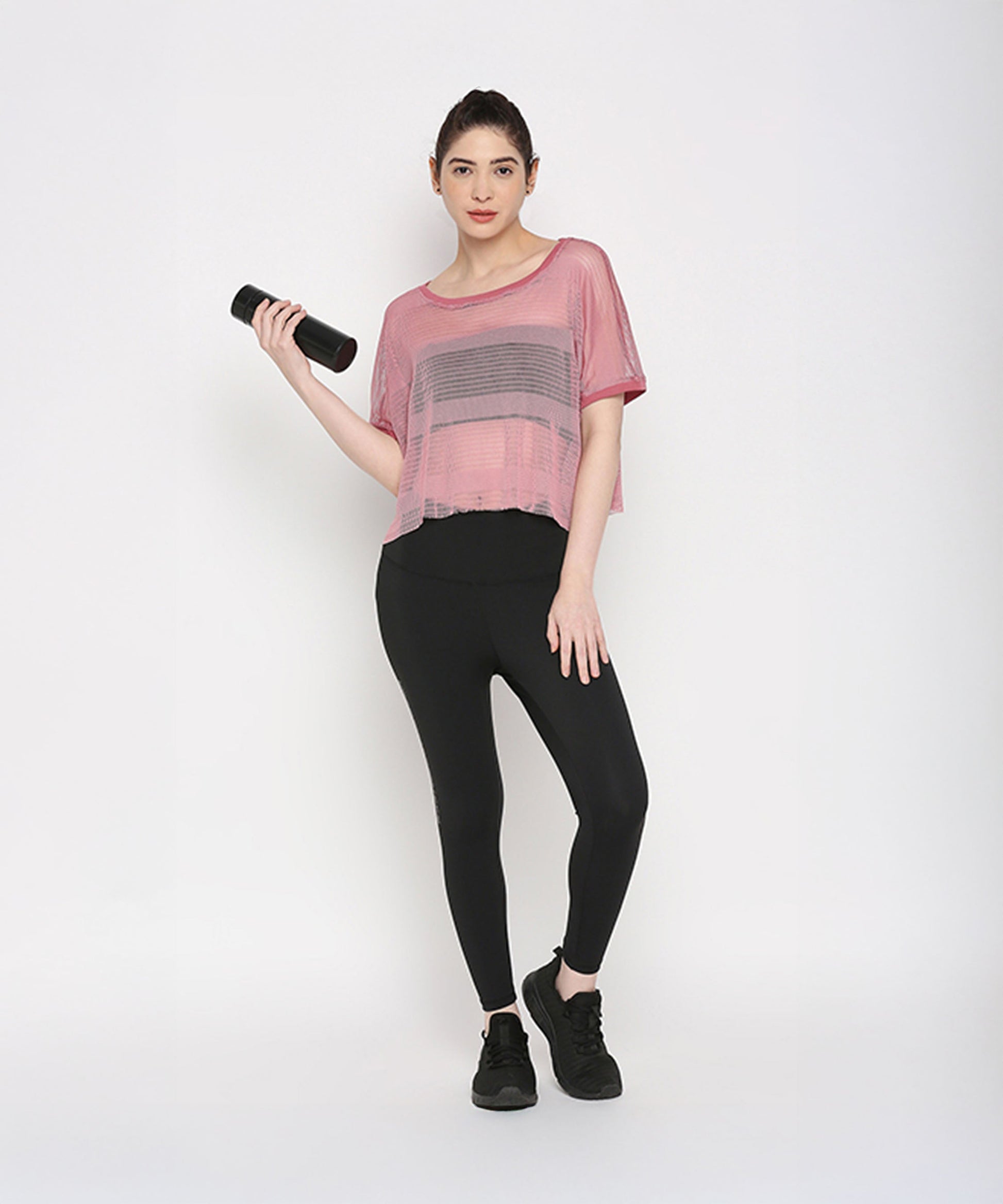 Pink netted top for women paired with black leggings and holding a fitness bottle