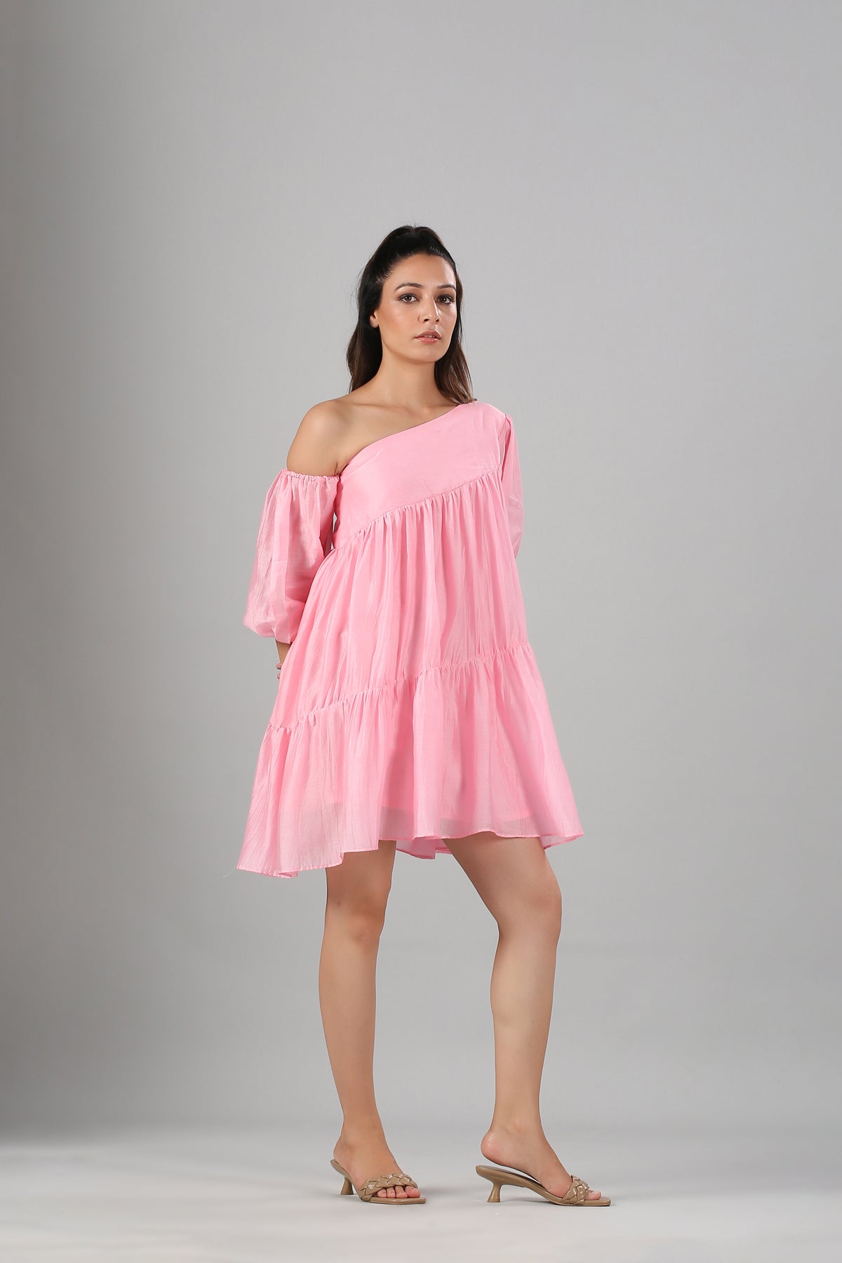 Stylera model wearing pink off shoulder dress with one puff sleeve and tiered mini skirt for summer events