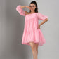 Model wearing Stylera pink off shoulder dress short tiered babydoll silhouette with puff sleeves and sandals