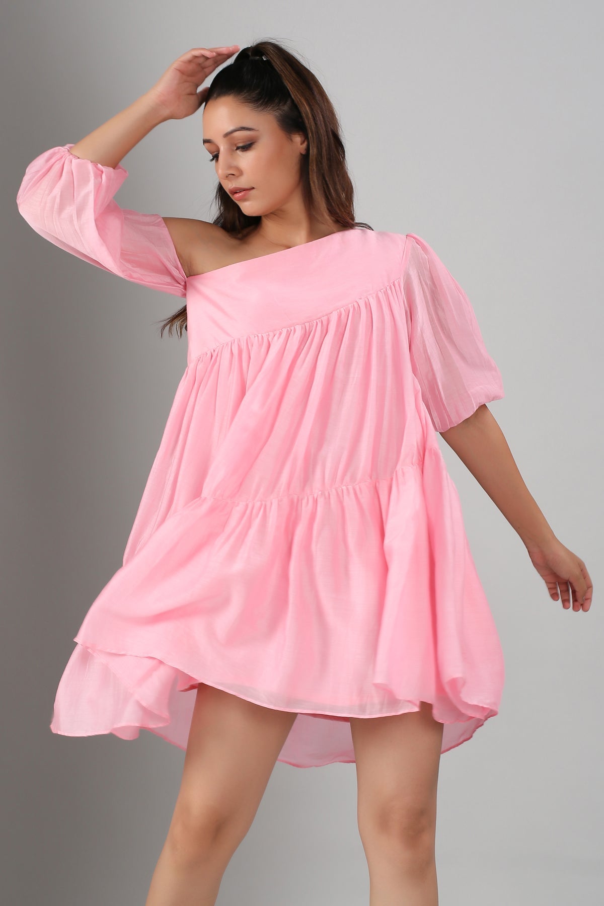 Stylera model wearing pink off shoulder dress loose tiered flowy fabric with elbow sleeves