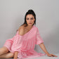 Stylera model seated on studio floor wearing pink off shoulder dress with relaxed sleeves and summer casual style