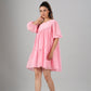Woman modeling pink off shoulder dress by Stylera with tiered hem puff sleeves and relaxed fit