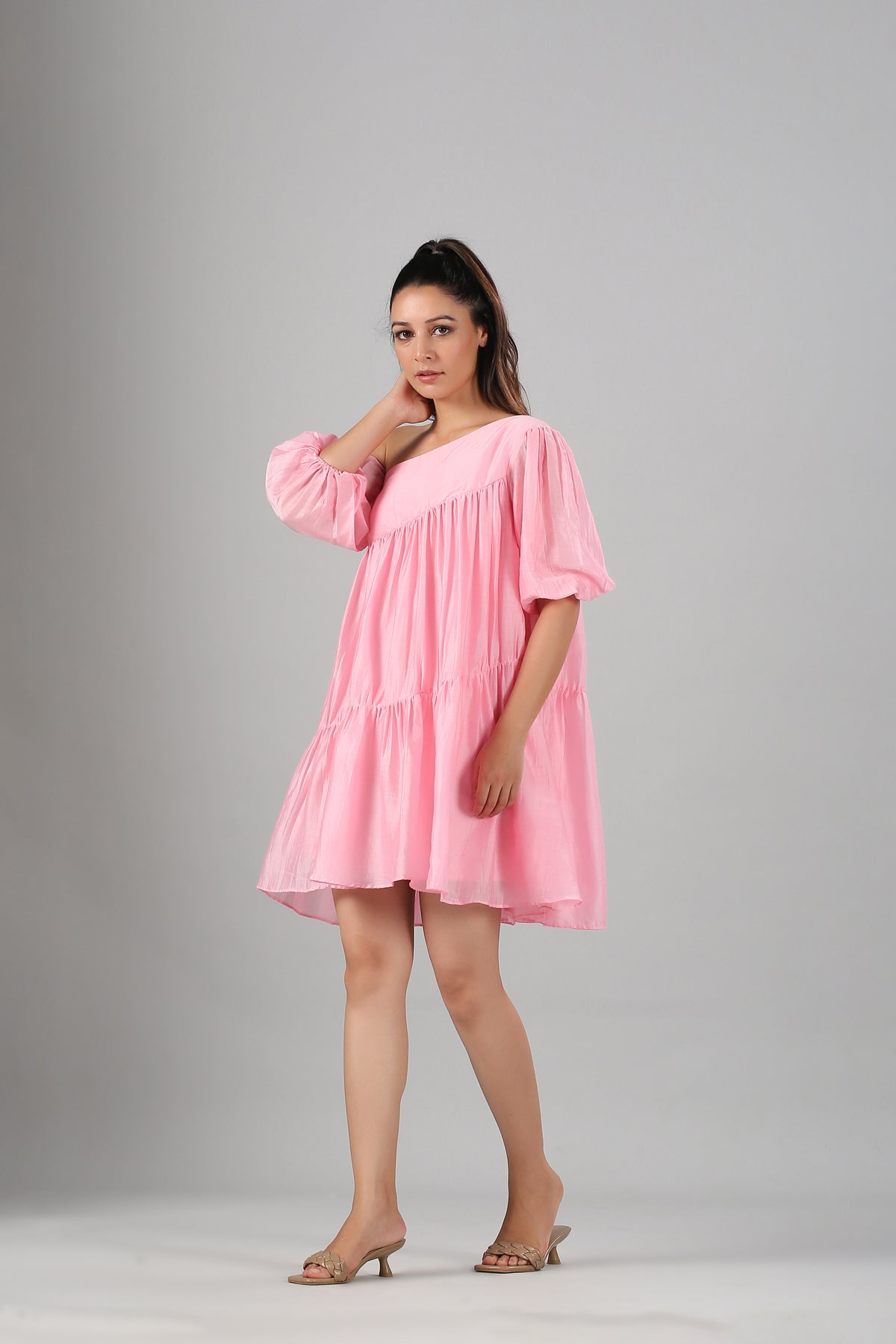 Woman modeling pink off shoulder dress by Stylera with tiered hem puff sleeves and relaxed fit